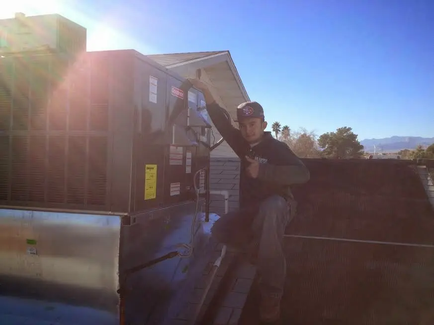 HVAC technician performing AC Tune-Up on a rooftop unit in Ridgecrest