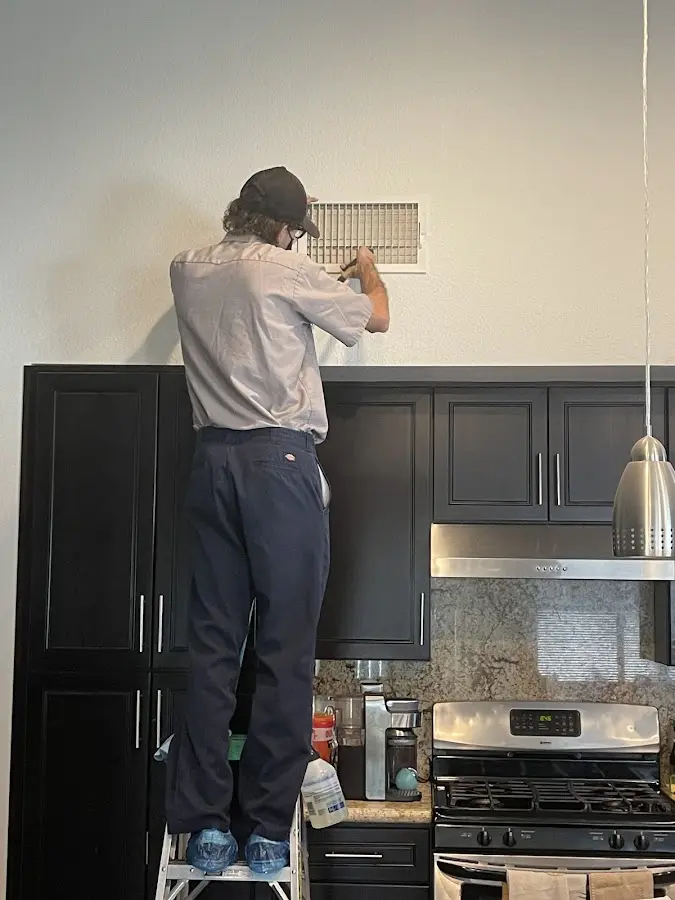 Technician inspecting an air vent during HVAC service in Ridgecrest